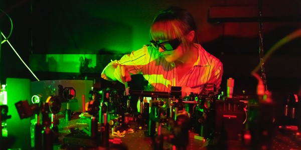 Quantum information transport experiment A photo of a researcher, Bereneice Sephton, wearing protective goggles and manipulating a component on an optical bench